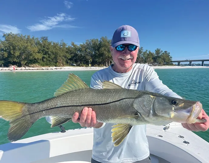Fisherman on a boat holding a snook